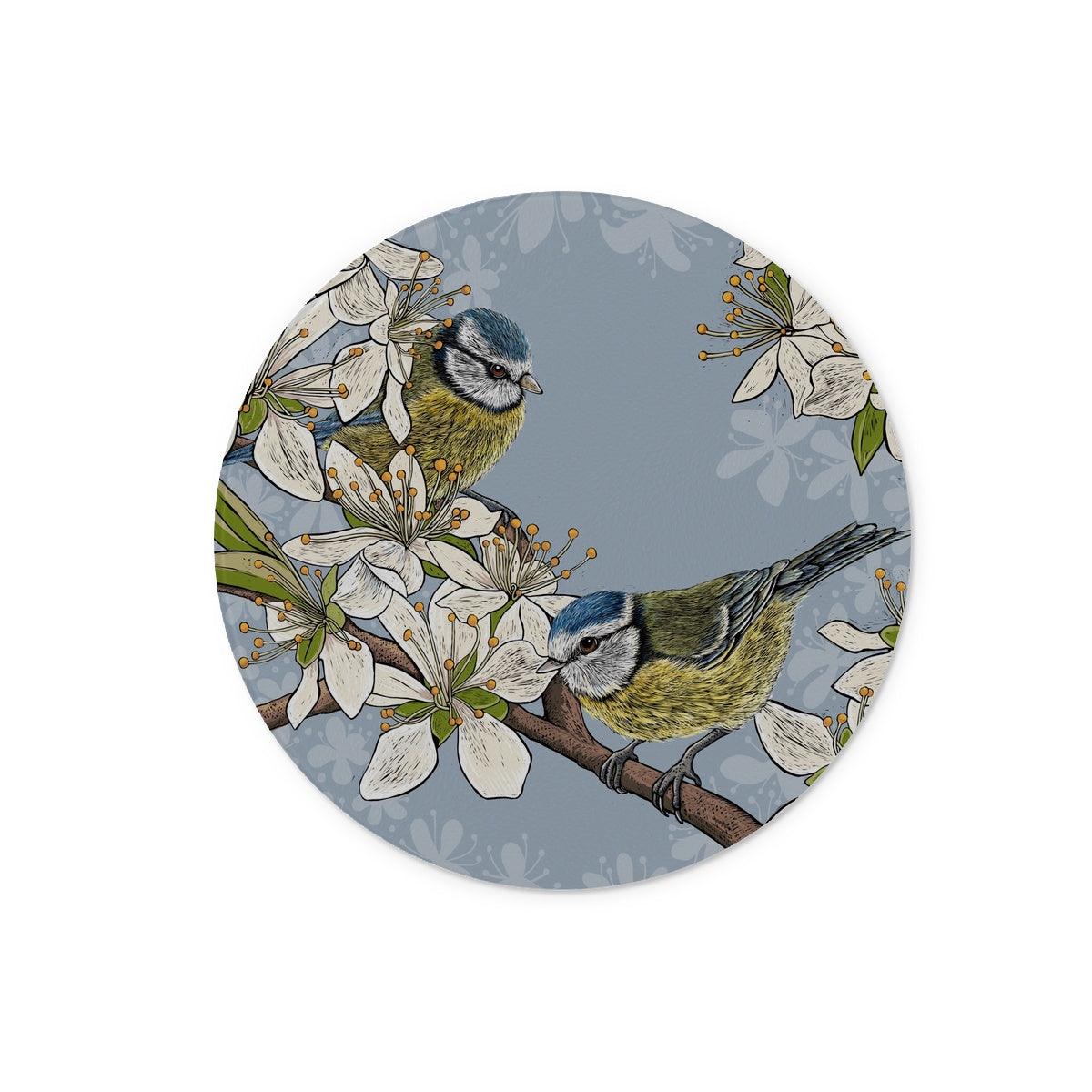 This design from Fox and Boo depicts two cute blue tits perched on stems of a hawthorn blossom tree, background is grey blue.